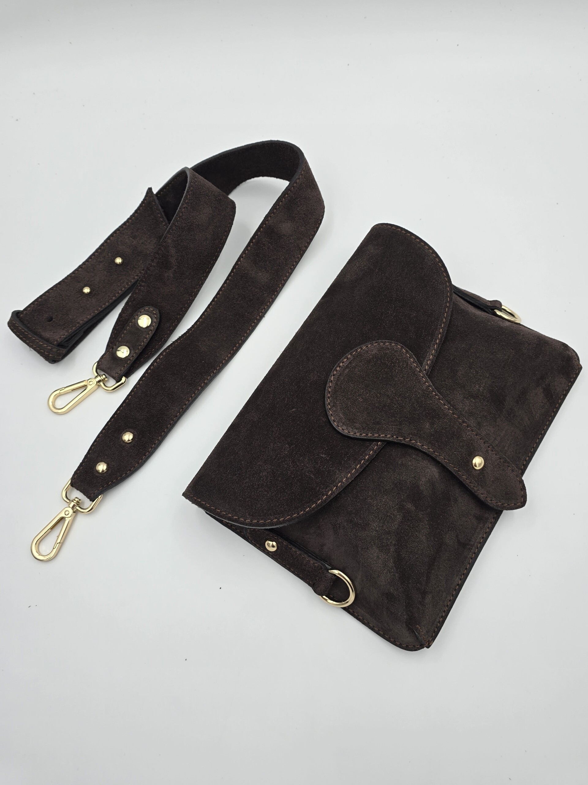 Tamsiai ruda, šokolado atspalvio versta odinė rankinė–delninė su auksinėmis detalėmis ir nusegamu dirželiu